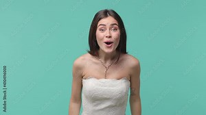 Excited joyful funny bride young woman 20s in beautiful white wedding dress posing isolated on blue turquoise background studio. Wedding concept. Waving meeting greeting with hand as notices someone