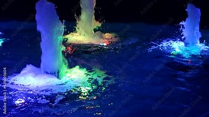 Fountain in water illuminated by colorful lights at night. Flow of water rising up and illuminated by multi-colored light. Fountain fountaining gushing. Water pressure, water head. Deco decorations Stock Video