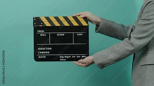 Movie slate or clapperboard hitting. Business woman holding empty film slate and clapping it. yellow and black clapper board isolated on blue green background. video film production.