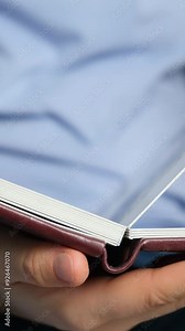 Turning the pages of a photo book with thick pages, vertical slow motion