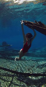 Beautiful sexy freediver woman posing underwater in transparent blue lake. Freediving in fresh water lake
