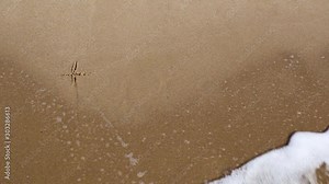Handwritten time word on a sandy sea beach is washed by the sea wave with foam on a summer sunny day. Disappearing time concept