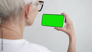 Old Person Touch Screen Smartphone with Green Chroma Key Close-up. Older 50s Female Hold in Hand Cell Phone Clicking Mock-up. Concept Watch and Show Internet Social Media, Read News, App e-Shopping 4k