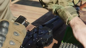 Loading a gun magazine with bullets. a close up shot of hands loading a magazine clip with bullets.