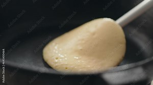 Morning. A pregnant girl turns over lengths with a spatula on the kitchen table. General view: the expectant mother flips pancakes in a frying pan, masters new recipes for preparing breakfast, dough