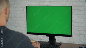 Man Typing on Keyboard and Looking at Green Screen Computer.Chrome key On Display