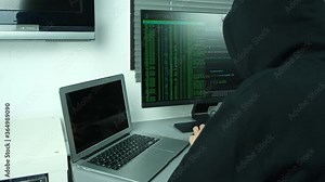 masked hacker using computer to hack data organizing massive data breach attacks on corporate servers located in a secret underground place wearing a black hoodie black cap and a scarf hidde identity