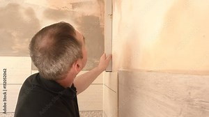 Construction worker measuring wall's straightness with spirit level