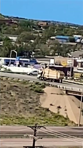 Large tan & white commercial front loading hydraulic trash garbage truck vehicle in the distance