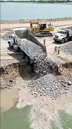 Dump Truck Unloading Rocks Into Water – Extreme Road Base Construction