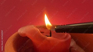 Red candle with yellow flame lit and blown out with smoke against red background in slow motion