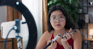 Instructions for contouring face with bronzer. A woman with Asian beauty is live streaming on social media, a girl uses a light ring, and works online giving beauty advice. Stock Video