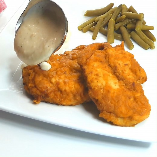 Chicken Fried Chicken with Country Gravy is a true family favorite! Crisp, breaded chicken smothered in a spicy, creamy gravy. Dinner never looked or tasted so good! https://www.favfamilyrecipes.com/chicken-fried-chicken-with-homemade-country-gravy/ | Favorite Family Recipes