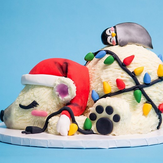 Have you ever wanted to cuddle a cake before? Because this one is beary cute. This polar pal has been hard at work on his Christmas decorations 🥰 Those fondant lights are wrapped around layers of raspberry buttercream and arctic blue raspberry cake — for a look that's as cool as the North Pole. | How To Cake It