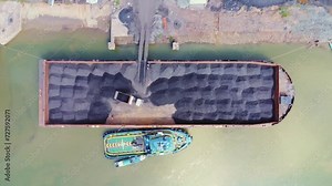 The process of loading coal onto barges using heavy transport cars
