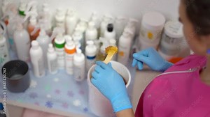 The hair removal specialist stirs sugar paste with wooden stick. Sugaring salon