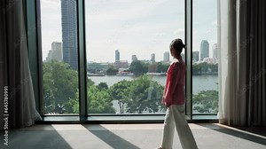 Ethereal woman walk to a big window, her eyes filled with vision and contemplation. Captivated by the expansive view beyond, she embodies a moment of introspection, wonder. High quality 4k footage