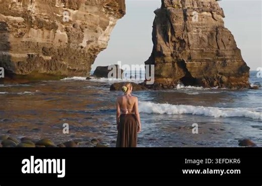 A serene late afternoon at the rocky coastline of El Salvador, featuring a female model observing the ocean Stock Video Footage - Alamy
