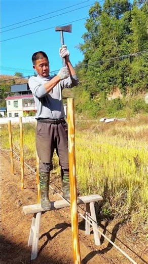 Rural Construction: Man Uses Axe to Sharpen Fence Post Piles