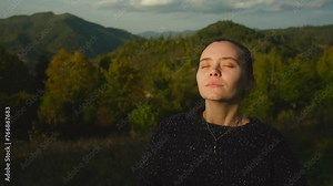 Beautiful young woman enjoying fresh air on top of the mountains. Female hiker contemplates scenic nature landscape view after climbing the mountain