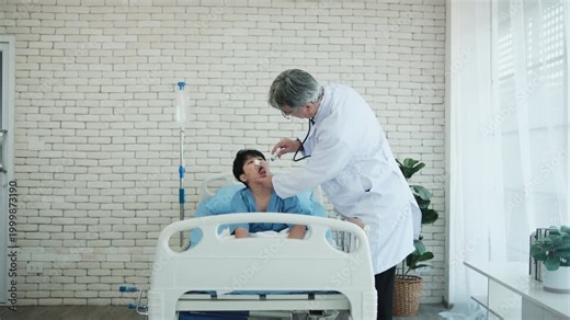 Male professional White doctor checkups Asian boy's throat cavity, healing nosebleed patient on bed in child hospital, pediatric ward, kid illness healthcare consultation, and medical diagnosis exam.