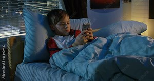 Boy text messaging while lying in bed