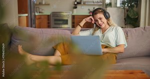 Laptop, headphones and student on sofa in home typing online for remote or distance learning. Technology, assessment task and female person on couch in a house for elearning, studying or development Stock Video