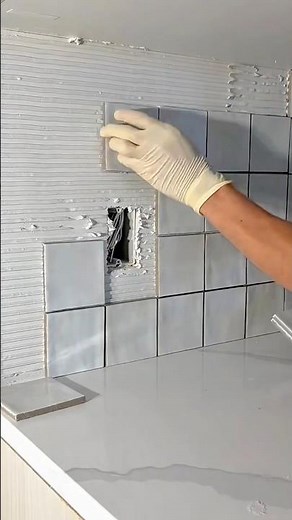 Carefully Installing a Modern White Tile Backsplash Around an Electrical Outlet
