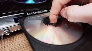 Compact disc is ejected from the DVD player. Male hand unloads CD from a CD player tray close-up. Music, movies, or data recorded on a laser optical information storage medium. Unloading Compact Disc