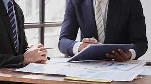 Young colleagues discuss business and analytical price charts using calculators and laptops to calculate financial, tax, accounting, statistics and analytical research ideas.