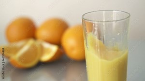 Ice cube falling in glass with orange juice, super slow motion