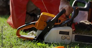 Man pull starts a chainsaw on grass - close up on pull cord being pulled