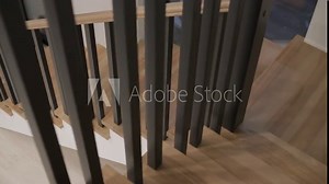 A top-down view of modern wooden stairs with black vertical balusters, showcasing the contrast of natural wood against a minimalist white background
