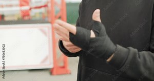 Close-up view of a strong boxer man putting on black boxer bands in the outdoor gym. Work out motivation