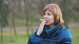 Stylish blonde woman standing and smoking a cigarette in an alley in slow motion