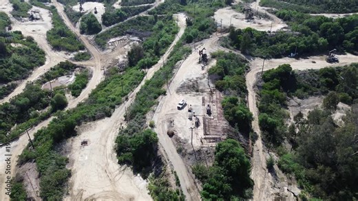 Central Inglewood Oil Field shows clustered pumpjacks, utility poles, service routes south of Kenneth Hahn State Recreation Area. Mixed vegetation, exposed soil, terrain in Los Angeles, CA