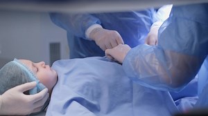 Child on the surgery table. Medics wearing surgical gloves adjust the operating diaper
