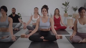 Female instructor and group young people practicing yoga trainer exercises indoors. Concentrated meditating persons in class. Healthy lifestyle in community, wellness and daily routines