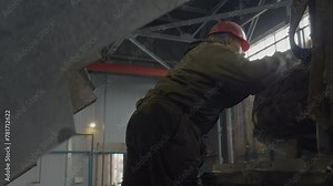 Mechanic climbs up the industrial machine at the facility. Mechanic deals with the maintenance of the heavy industrial machinery. Mechanic repairs the industrial machine inside the workshop.