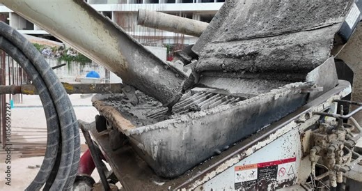 wet concrete pouring from a mixer chute into a pump hopper.