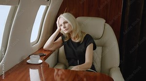 Sad rich mature business woman travels on private plane. Portrait of depressed senior woman flying in first business class airlines