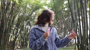 4k slow motion young asain woman blowing soap bubble in the spring bamboo park
