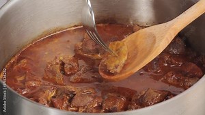 Testing with a fork to see if the meat is cooked
