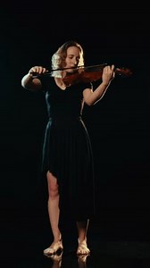 Amazing concert of classical music, female musician playing violin in darkness. Contemporary art performance on stage, vertical video, enjoy beautiful sounds of viola, talented and inspired violinist