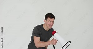 Angry fitness coach shouts using megaphone at training on white background. Strict guy with furious facial expression express negative emotions