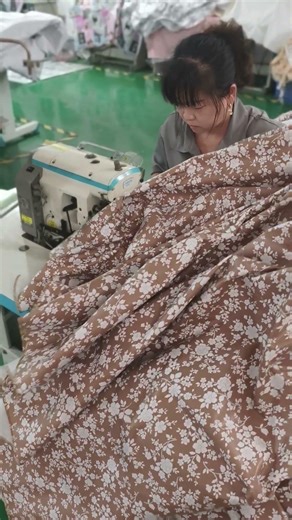Experienced auntie is wrapping the edges of the tablecloth with a sewing machine