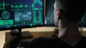 hacker works at a computers and drink tea in a dark office room.