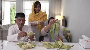 senior muslim couple and daughter making ketupat for eid fitr mubarak celebration at home