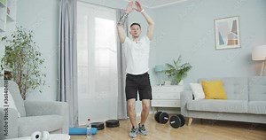 Muscular sportsman working out to bulk up at home. Attractive guy performing physical jump exercise, jumping jacks, side-straddle hop. Cardio workout, training, following healthy, wealthy lifestyle.