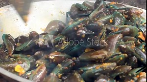 the process of cooking green mussels or Perna viridis, mixed with corn and spicy stir-fry spices.